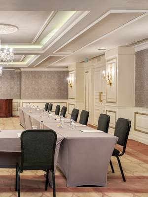 Elegant meeting room at Rixos Pera Istanbul arranged in a U-shape setup with covered tables, black chairs, water bottles, notepads, chandeliers, and classic interior décor.