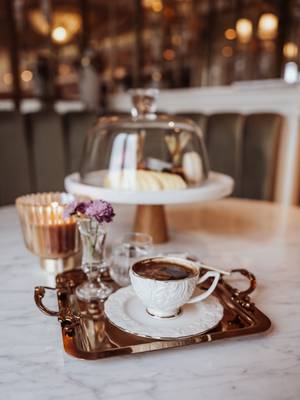 Close-up of an ornate white cup of Turkish coffee on a small copper tray and white marble table at the Era Lounge, Rixos Pera Istanbul.