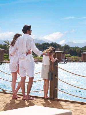 A family in white summer outfits enjoying a peaceful seaside moment at Rixos Premium Belek, Infinia Vacation Club.